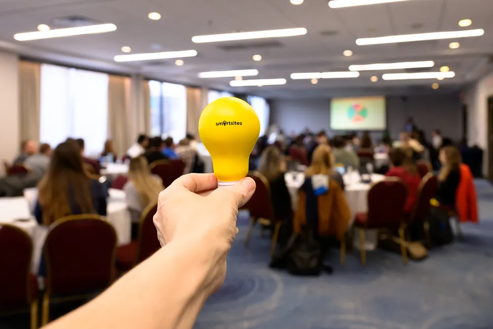 A SmartSites light-bulb stress ball held up at a company event